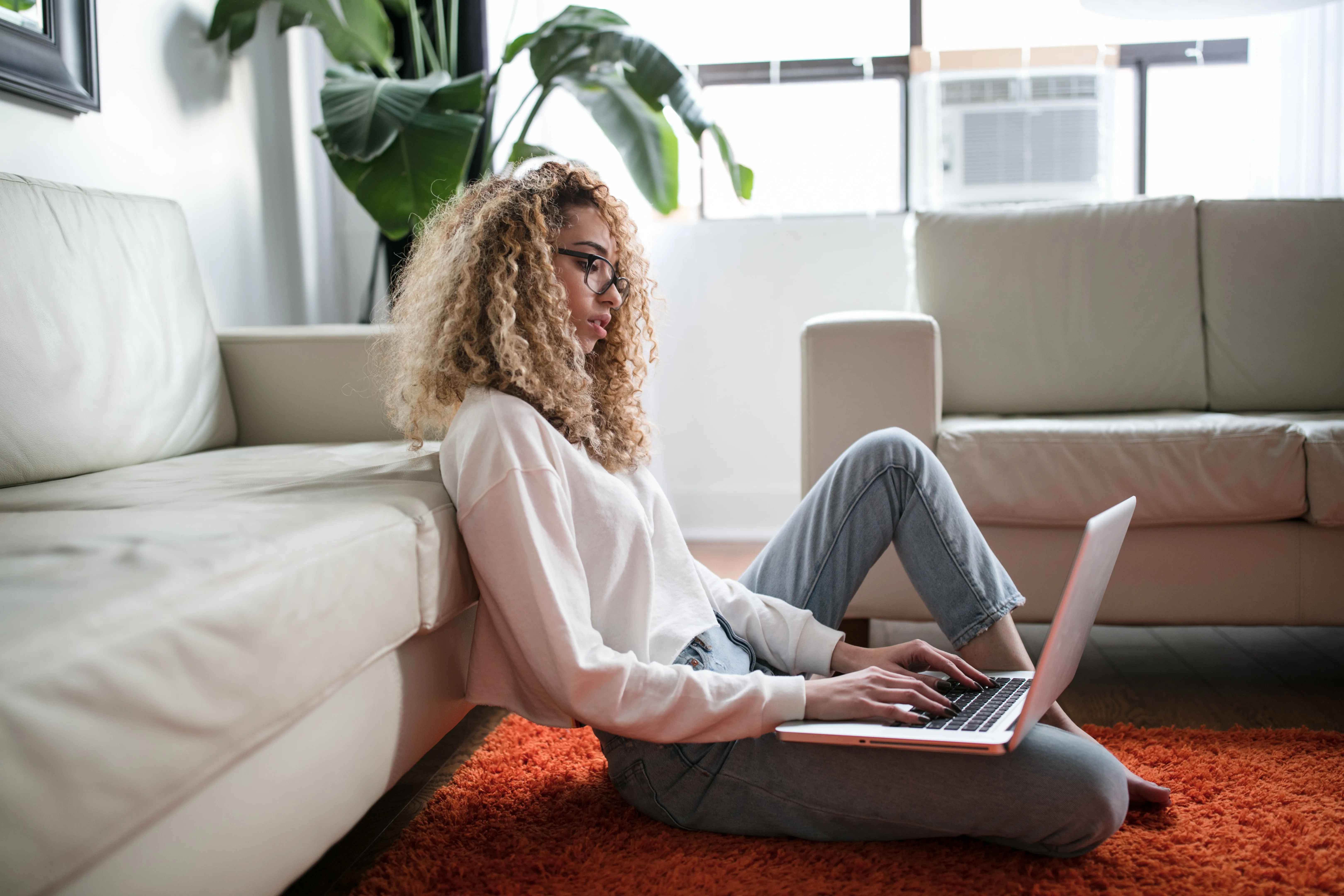 Woman working on her laptop while sitting on the floor 