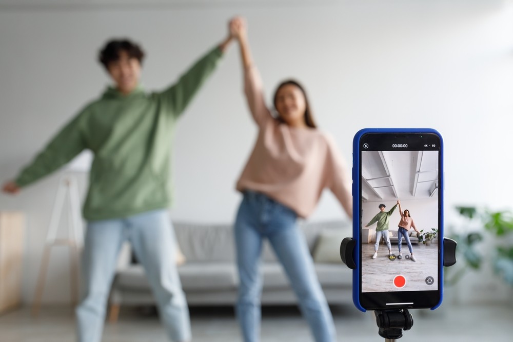 Closeup of a phone on a tripod recording two young people dancing.