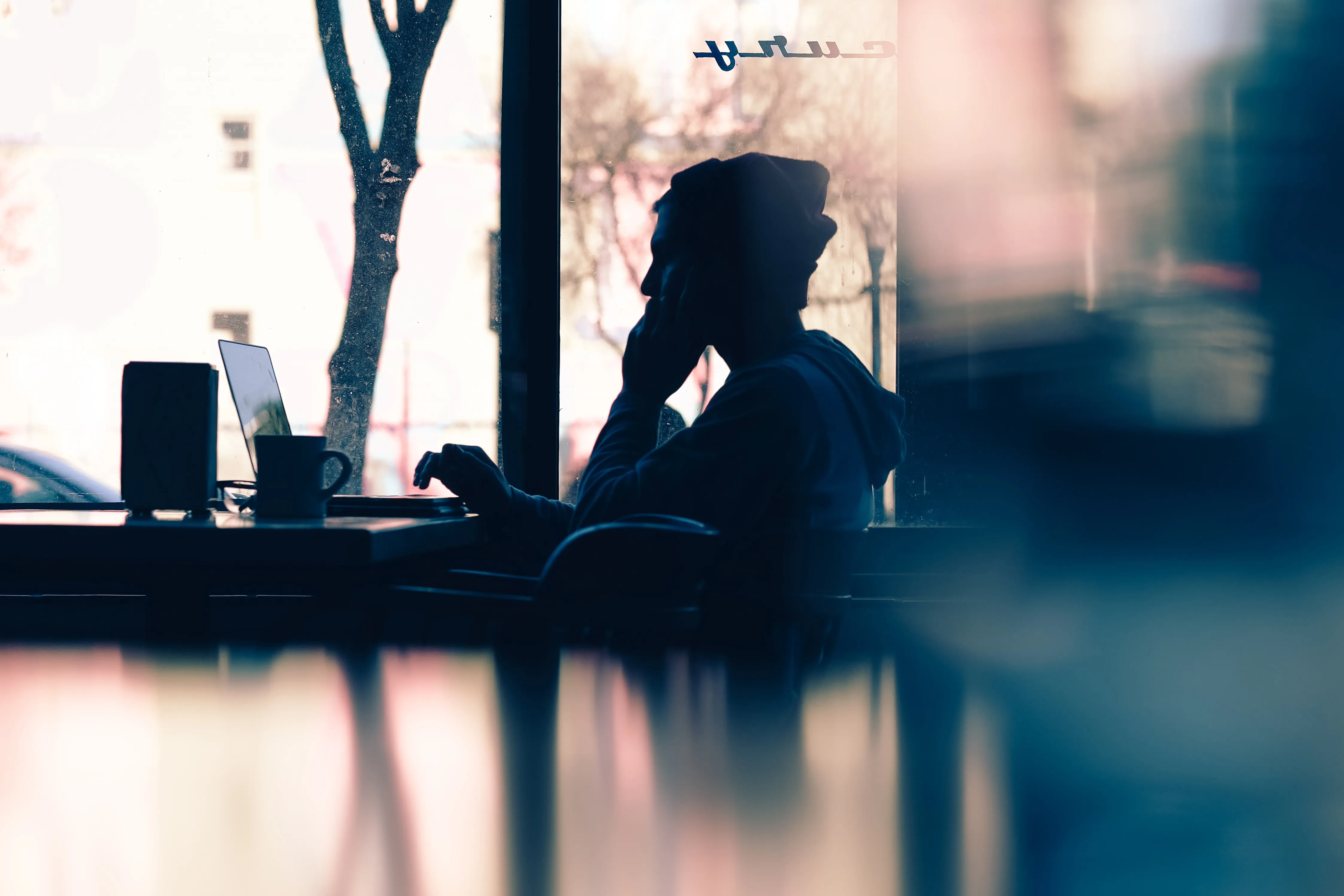 Man sitting at a desk in an office space working on a laptop.