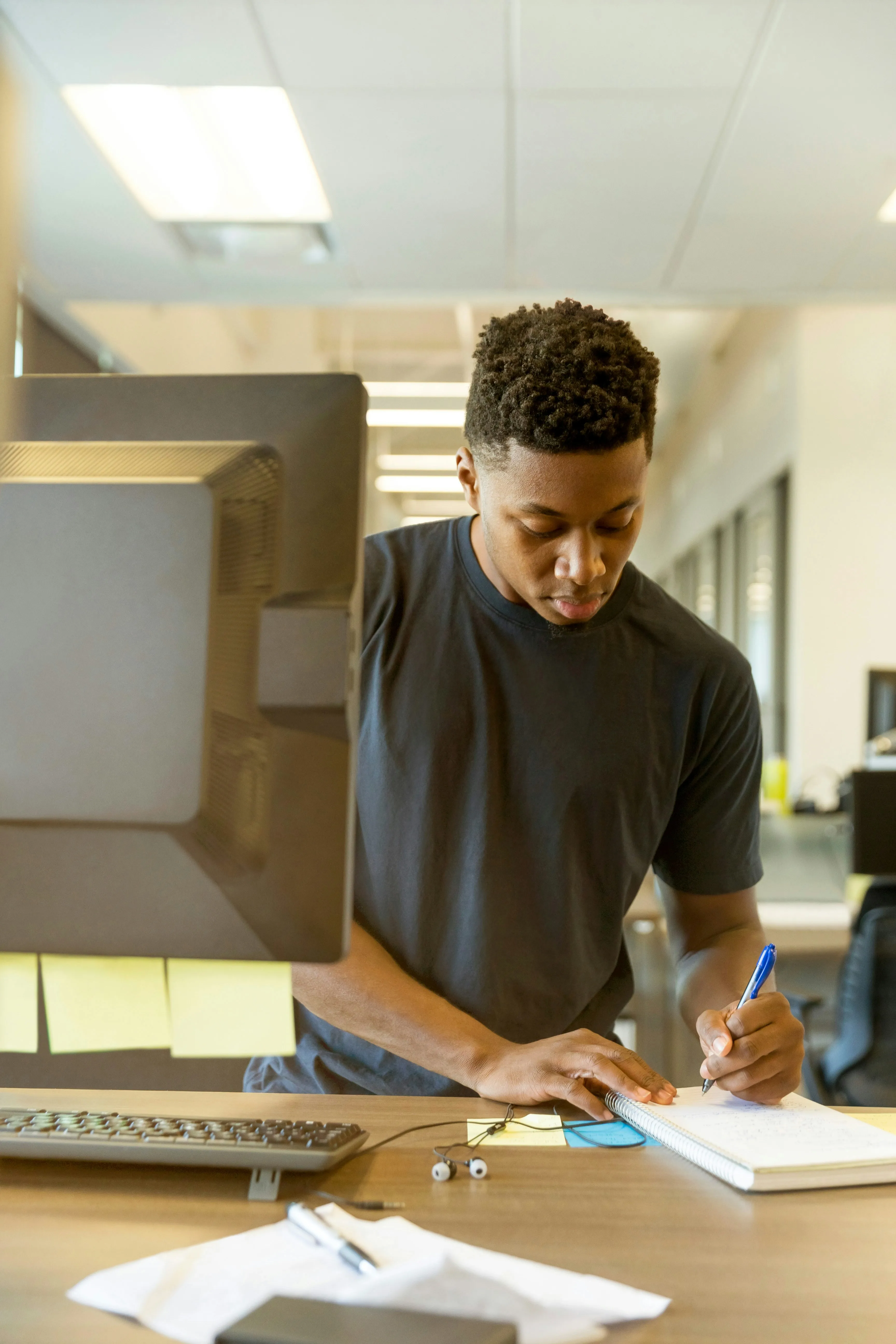 Man taking notes while working on the computer.