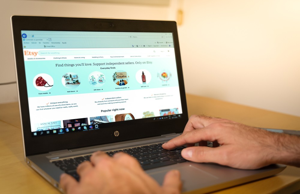 Hands typing on a laptop with the Etsy website open.