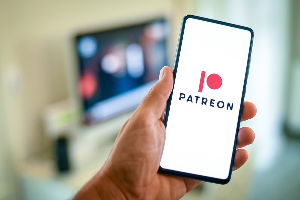 Closeup of a hand holding a phone that is opened to the Patreon app.