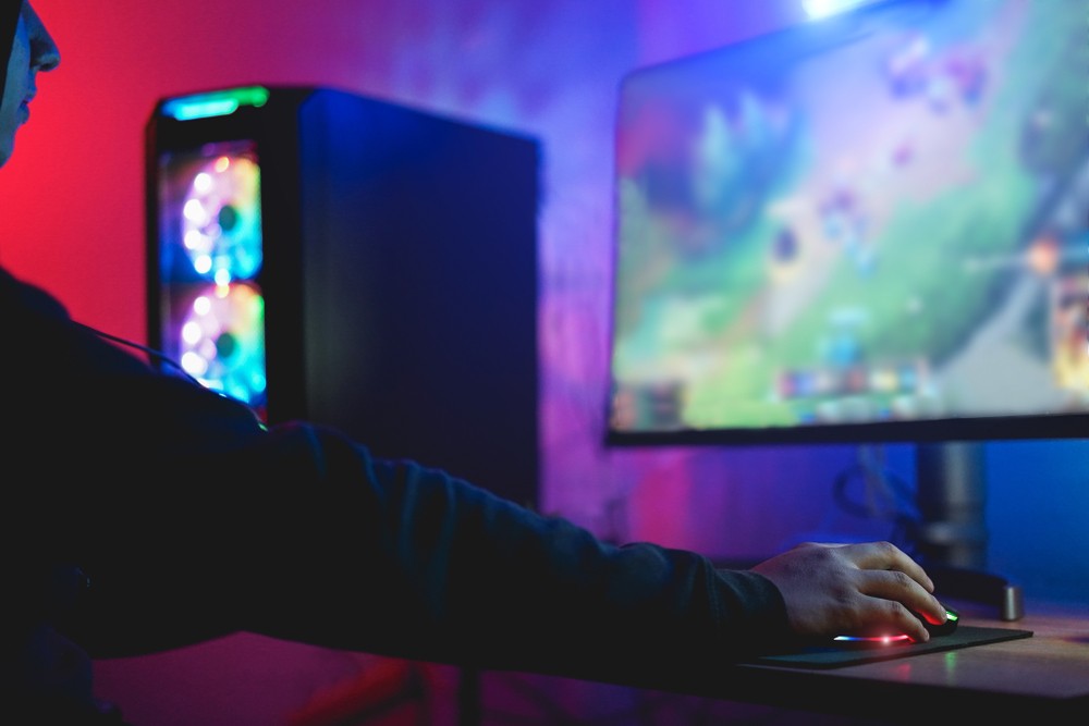 Image of young man playing a game with a colorful gaming setup.