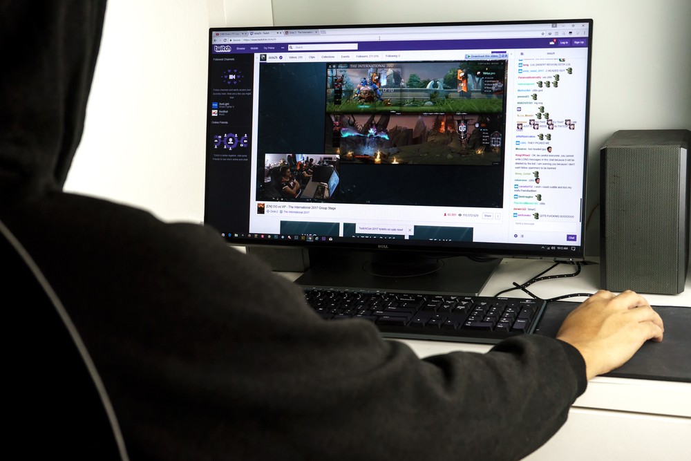Image of a the back of a young man gaming on Twitch on their desktop.